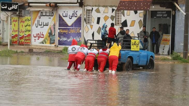 Des volontaires du Croissant-Rouge iranien aident les personnes touchées par les fortes pluies et les inondations dans le sud-ouest de l'Iran en poussant leur véhicule hors de la rue inondée. 