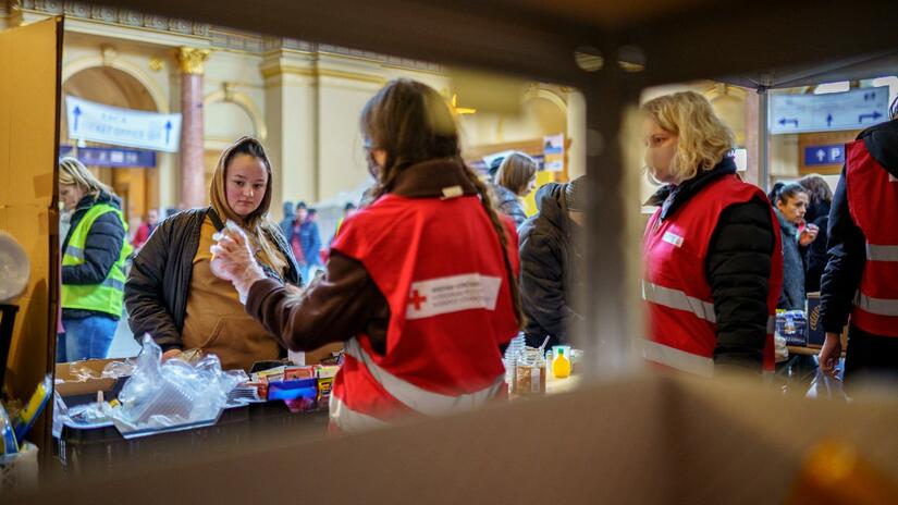 Une femme fuyant le conflit en Ukraine parle à des volontaires de la Croix-Rouge hongroise dans un Point de service humanitaire qu'ils ont installé dans la gare de Keleti pour accueillir les personnes arrivant d'Ukraine et leur apporter un soutien.