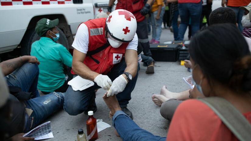 متطوع في الصليب الأحمر الهندوراسي يقدم الإسعافات الأولية لامرأة مصابة في سان بيدرو سولا كانت تهاجر شمالًا بحثًا عن حياة أفضل. 