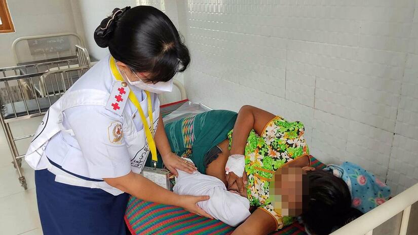 A Myanmar Red Cross hospital worker supports new mother, Moe Thuzar, to breastfeed her newborn baby.