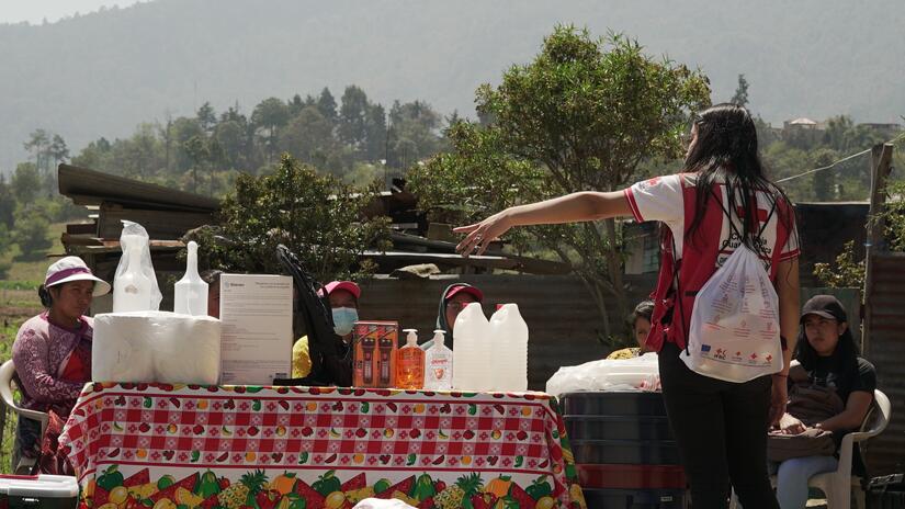 عاملة في الصليب الأحمر الغواتيمالي تقوم بتدريب اللجنة الصحية المحلية في زيكاراكوخ بشأن رسائل التثقيف الصحي الرئيسية وتزودهم بالمياه ومستلزمات الصرف الصحي والنظافة لتوزيعها. 
