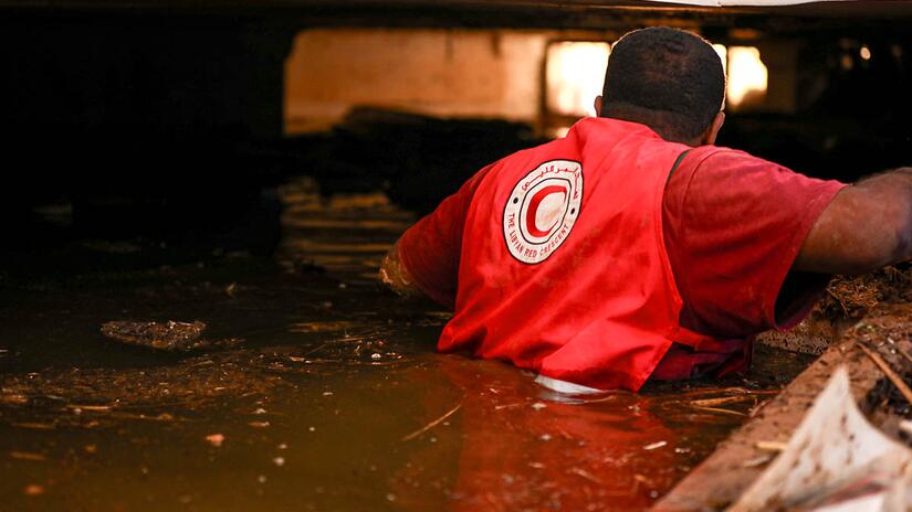 A Libyan Red Crescent volunteer crosses flood water in search of survivors from the devastating floods that hit Libya in September 2023.