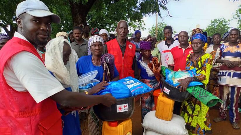 Personas desplazadas por la violencia en Burkina Faso se reúnen en un punto de distribución establecido por la Cruz Roja de Benín.