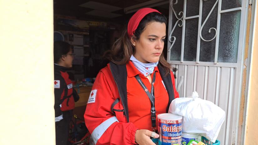 متطوع في الصليب الأحمر الإكوادوري يقدم الإمدادات للأشخاص المتضررين من الانهيارات الأرضية الناجمة عن الأمطار الغزيرة. 