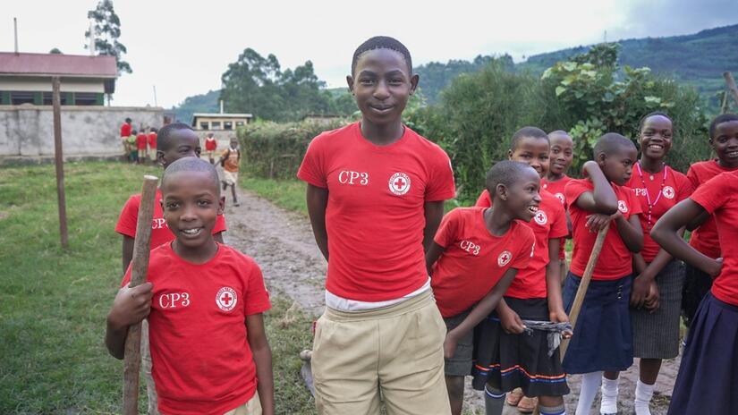 كوشابا، عضو نادي الصحة المدرسية في مويسي، أوغندا، يبتسم وهو محاط بزملائه الطلاب الذين يتعلمون كيفية الوقاية من الأمراض المختلفة. 