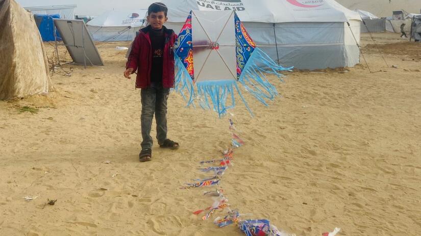 آدم، ابن عمرو، يلعب بطائرة ورقية في المخيم الذي تعيش فيه العائلة في رفح.