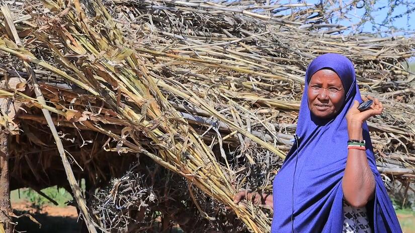 Mama Koos Yusuf Mohamed holds a bundle of the corn plant residue from her harvest, which is used for animal feed. 