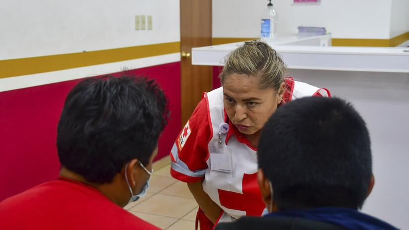 لوبيتا غونزاليس، أخصائية طبية في حالات الطوارئ الصليب الأحمر المكسيكي، تتحدث مع اثنين من المهاجرين في عيادة صحية في شمال المكسيك. 