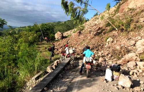 People in Haiti evacuate while navigating landslides caused by the earthquake.