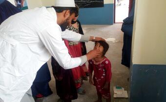 An Afghan Red Crescent volunteer administers an oral polio vaccine to a young child as part of its immunization campaign.