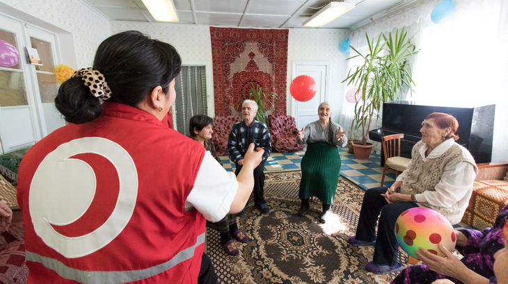 Una voluntaria de la Cruz Roja de Kirguistán juega con una mujer en un centro para personas mayores en Kara-Balta, Kirguistán
