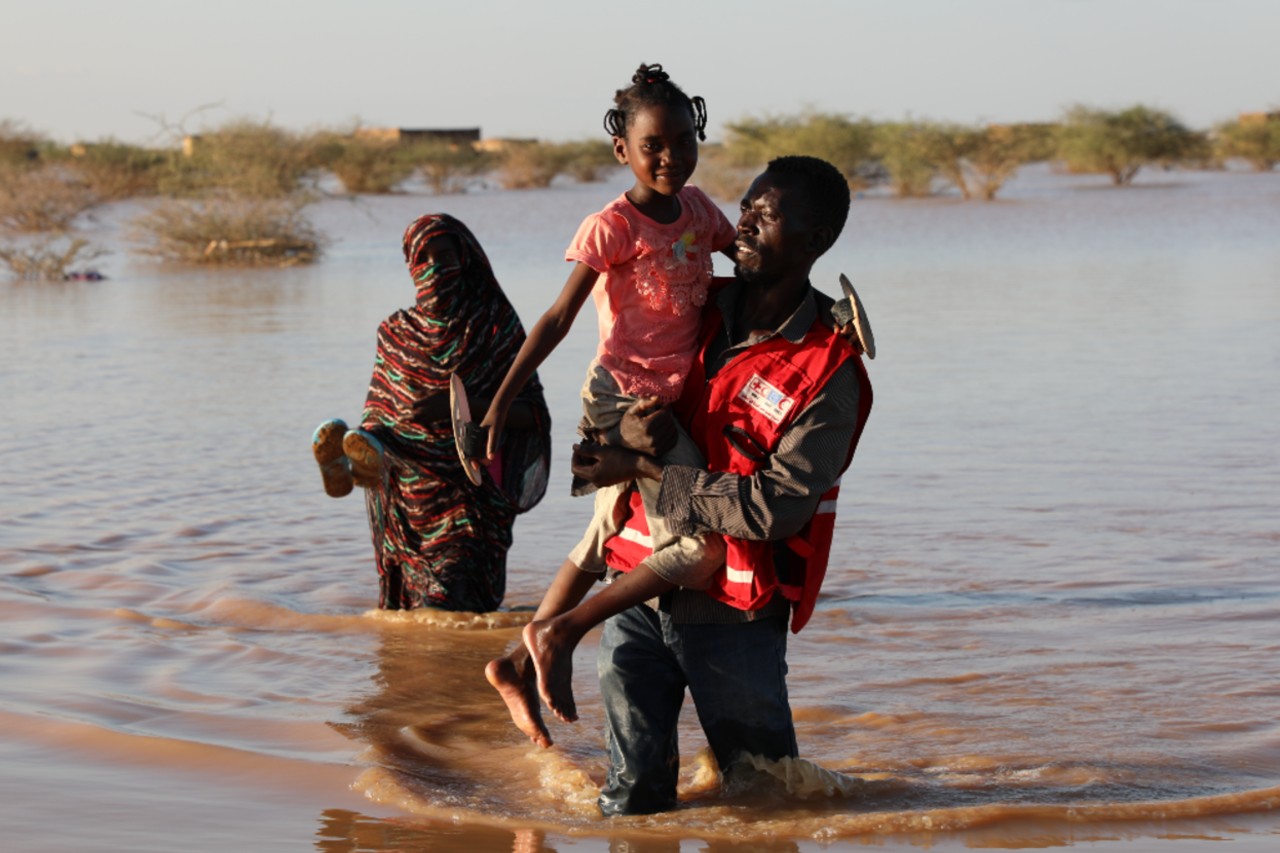 A volunteer from the Sudan Red Crescent carries a young girl to safety through flood water in River Nile state, Sudan in August 2020