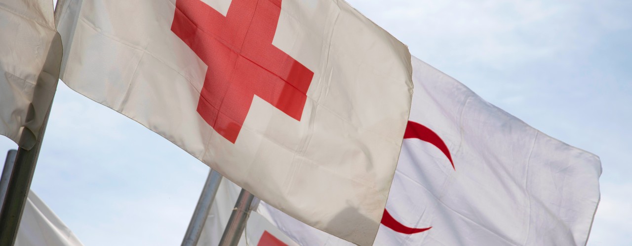 Red Cross and Red Crescent flags flying in the wind