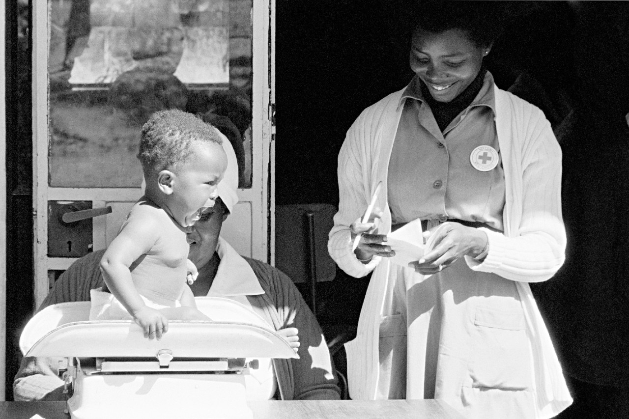Une infirmière de la Croix-Rouge pèse un bébé dans une clinique pédiatrique au Malawi en 1982