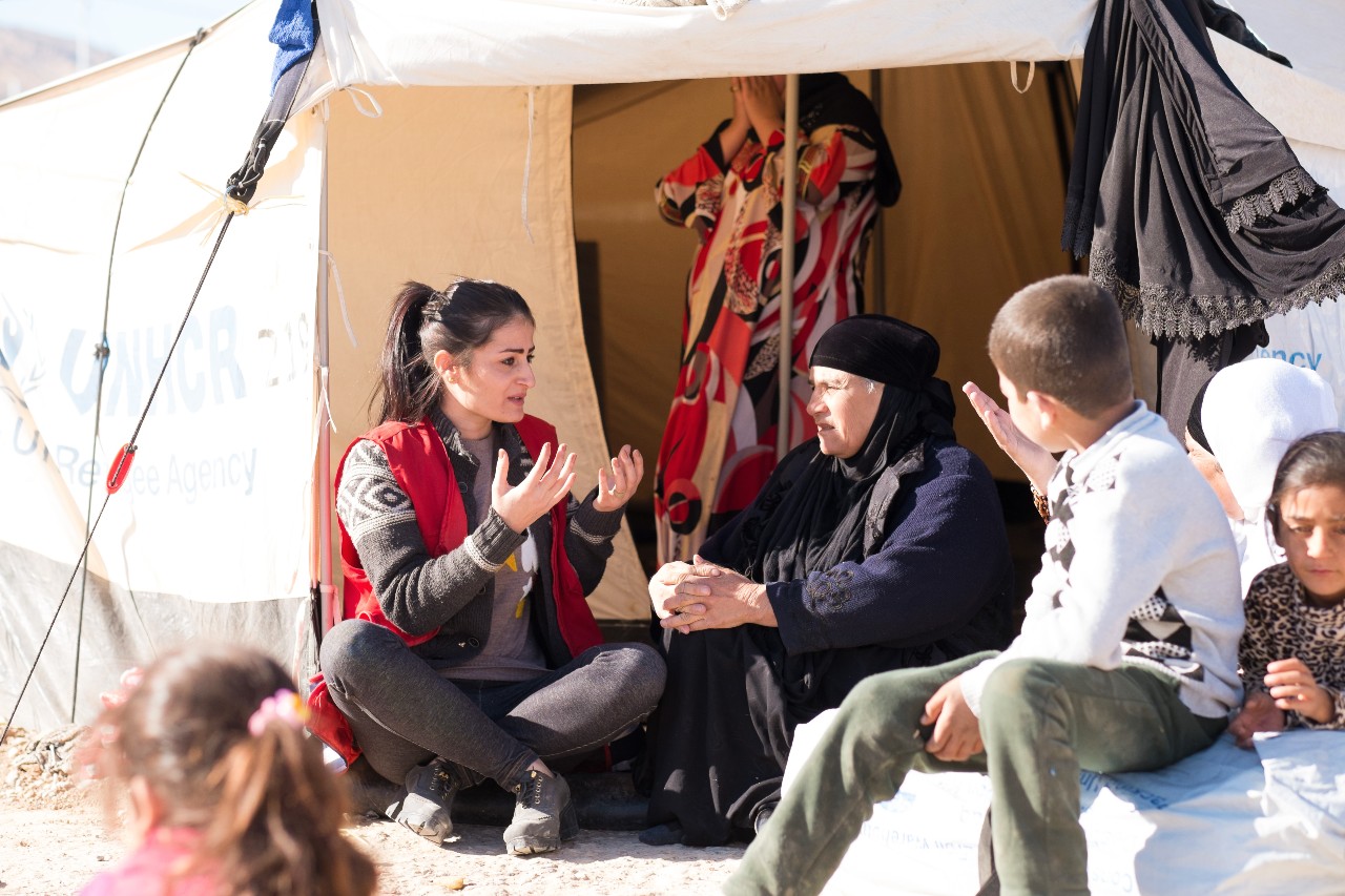 Una voluntaria psicosocial de la Sociedad de la Media Luna Roja Iraquí habla con una familia que escapó de Mosul a la seguridad de un campamento de socorro cerca de Dohuk