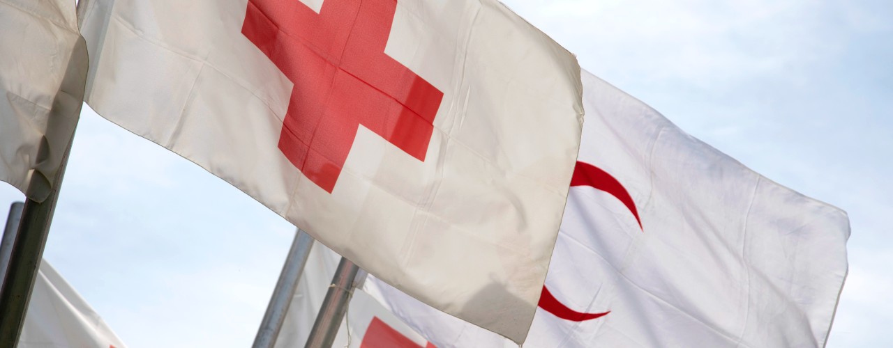 Red Cross and Red Crescent flags flying in the wind