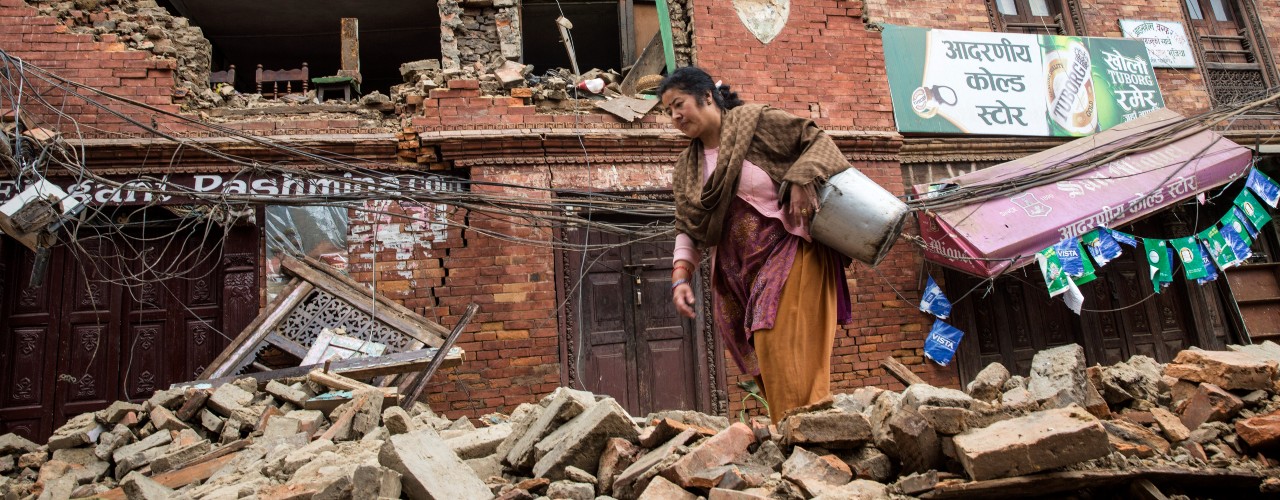 A woman walks through collapsed buildings and debris in Bhaktapur, Nepal following the devastating earthquake in 2015