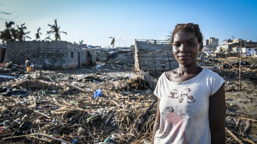 A woman in Mozambique stands in front of debris and collapsed houses that were destroyed by Cyclone Idai in March 2019