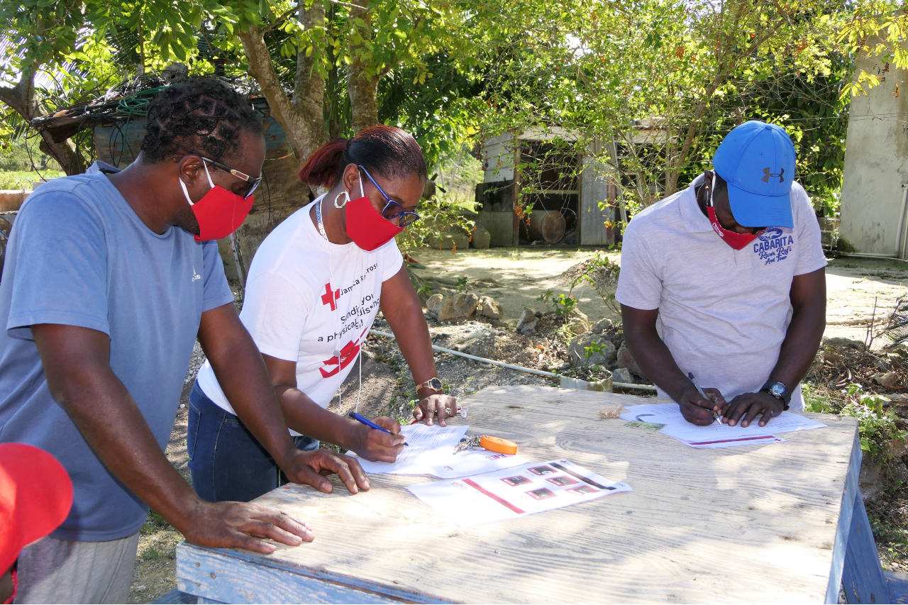 A volunteer from the Jamaica Red Cross helps river raft captains complete the registration process for cash cards, which were issued to persons who lost their income due to COVID-19. Across the Caribbean, persons working in the tourism industry were severely impacted by COVID-19 restrictions.