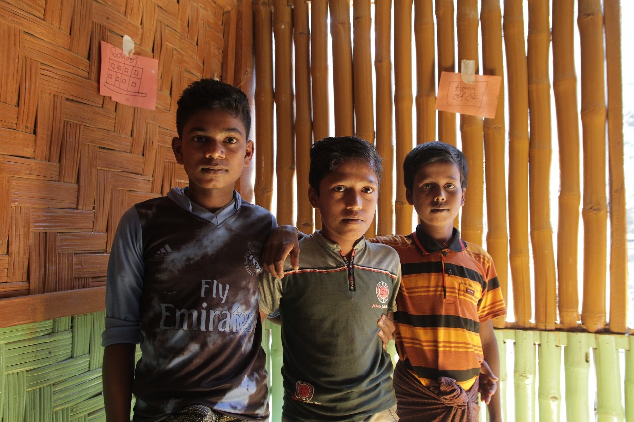 Three young boys, Mohammad, Anwar and Syed stand together in a community safe space run by the Bangladesh Red Crescent Society in Burmapara camp in January 2018