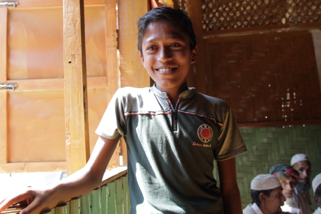 Anwar, a young boy from Myanmar stands in a community safe space run by the Bangladesh Red Crescent Society with support from the Danish Red Cross.