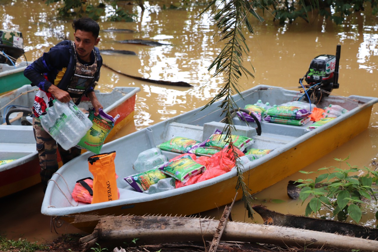 A Malaysian Red Crescent volunteer unloads relief supplies from a boat to assist communities in Terengganu state affected by severe flooding in summer 2021