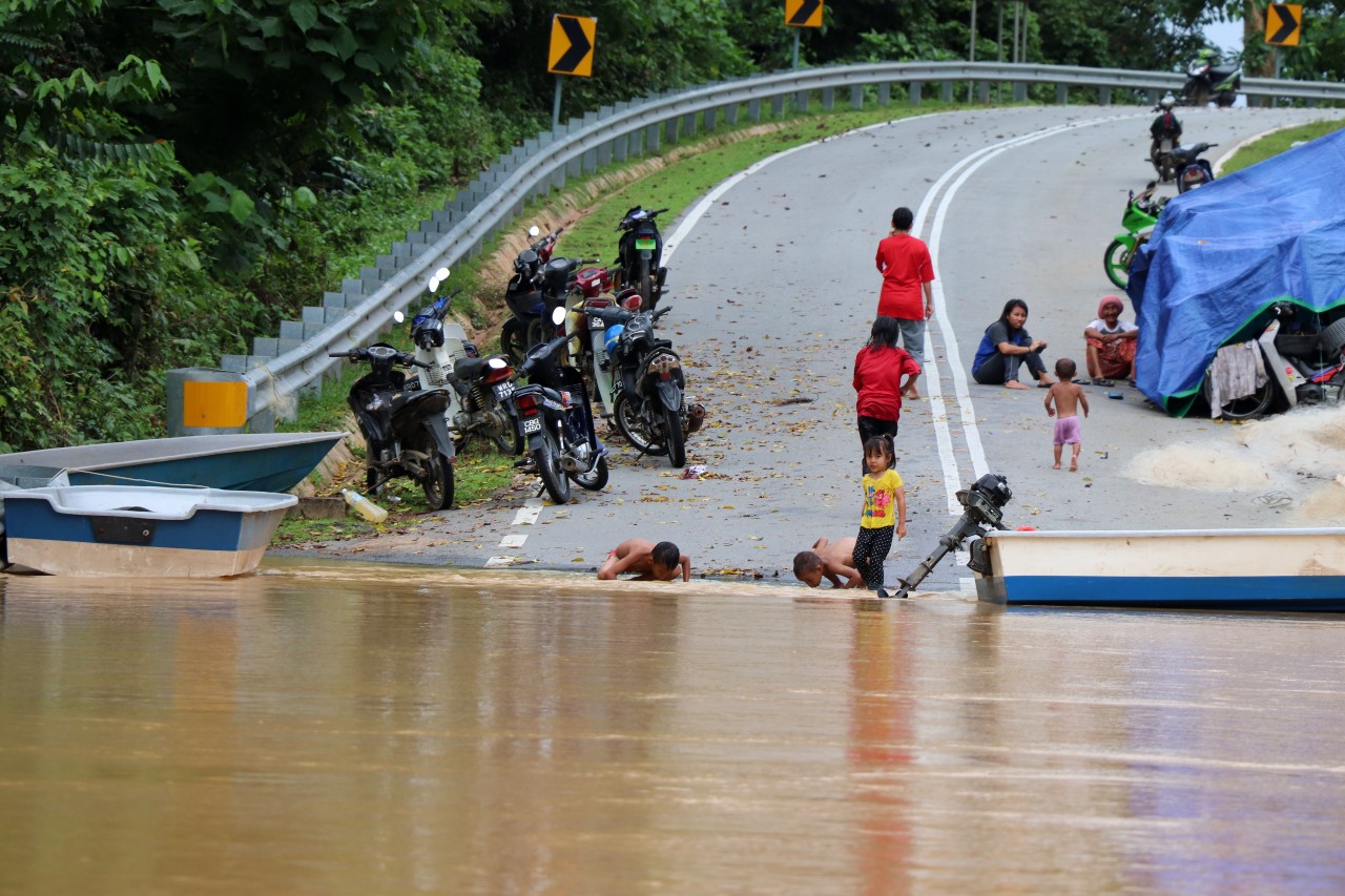 Malaysian Red Crescent volunteers provide assistance to families camping on roadsides waiting for flood waters to recede to reach their homes in summer 2021