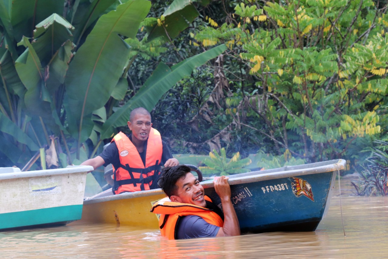 Malaysian Red Crescent volunteers steer a small boat through flood water in summer 2021 to reach stranded communities with essential supplies.