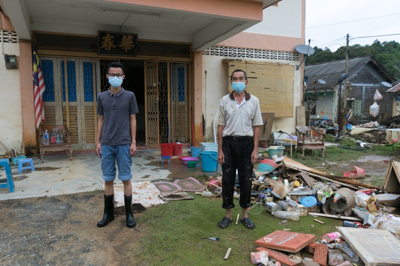 Two homeowners in Malaysia stand next to destroyed furniture and belongings following severe flooding in summer 2021