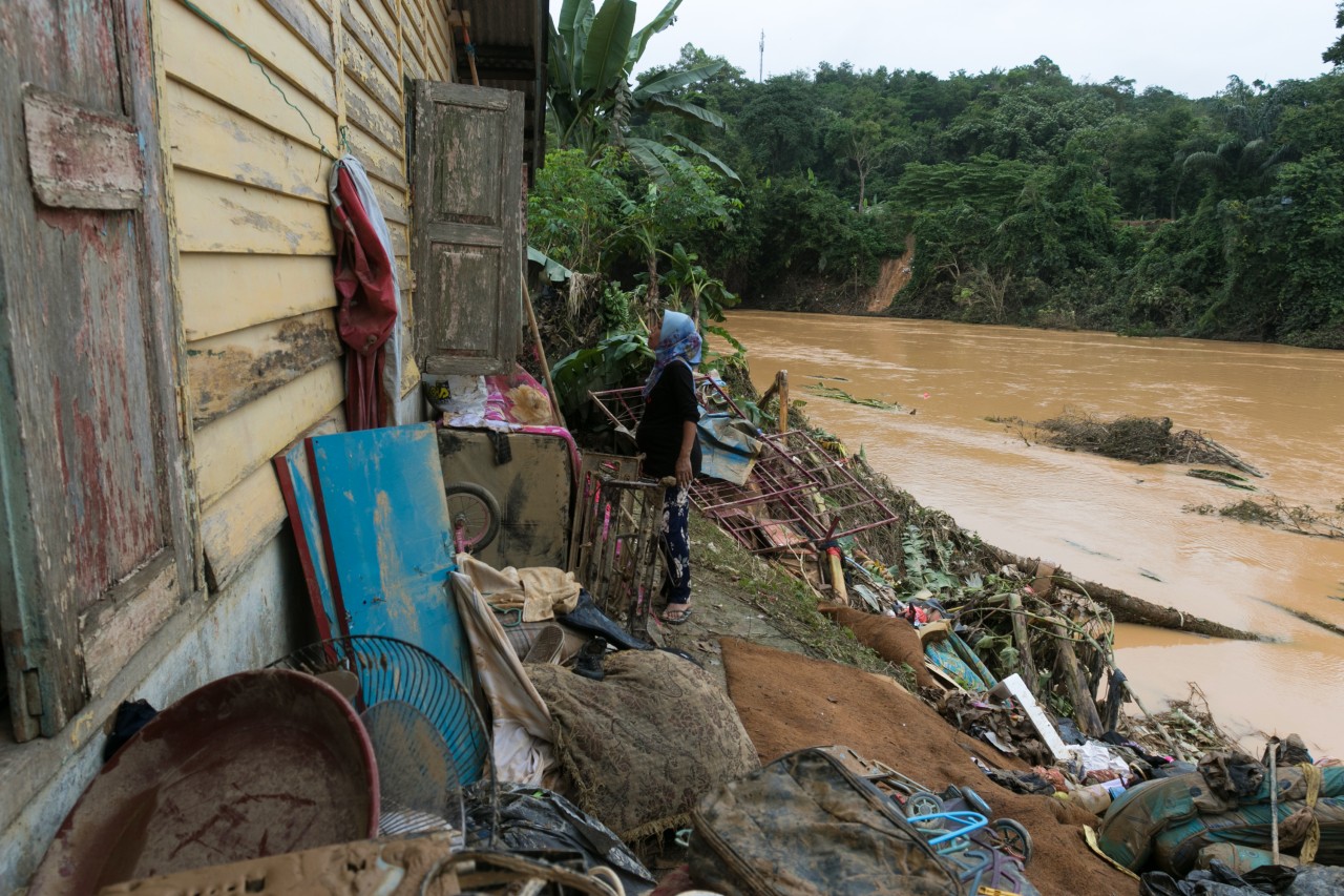 A woman looks through the window of her house in Terengganu, Malaysia that was badly damaged by severe flooding in summer 2021