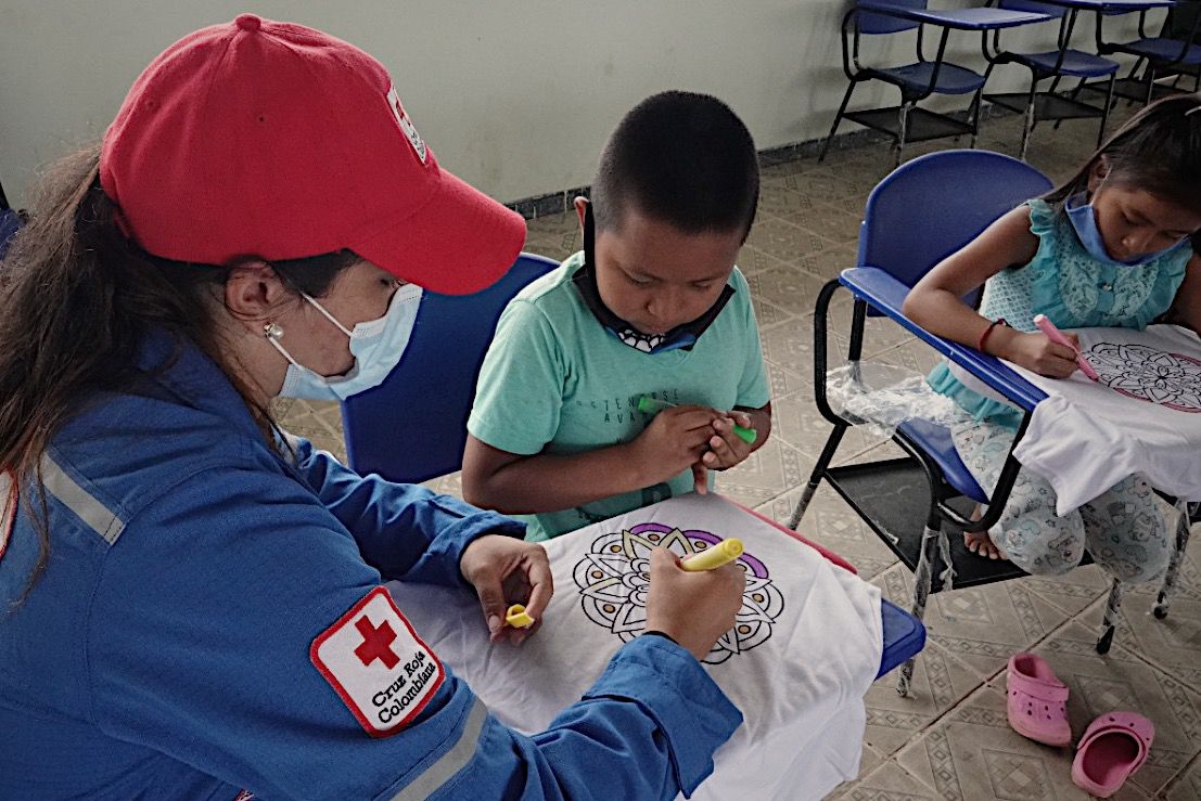 Laura Londoño, Voluntaria de la Cruz Roja Colombiana dibuja con un niño un mandala como parte de las actividades psicosociales.