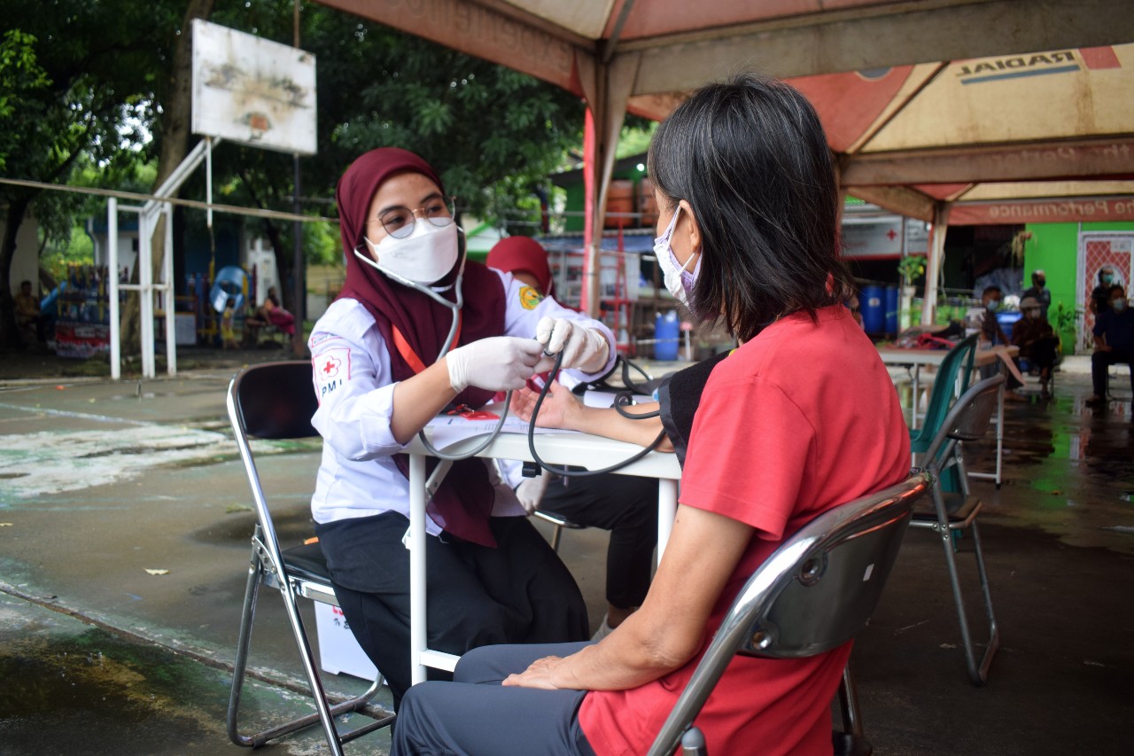 A volunteer from the Indonesian Red Cross in Tangerang, Indonesia performs a health check up on a woman before administering a dose of COVID-19 vaccine in January 2022.