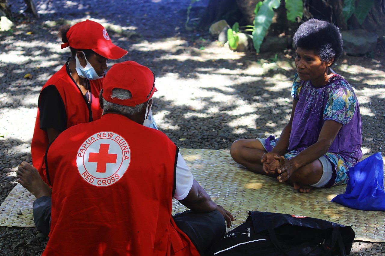 Papua New Guinea Red Cross volunteers sit down with a woman and respond to her concerns about getting the COVID-19 vaccine as part of its community engagement work to encourage people to get vaccinated.