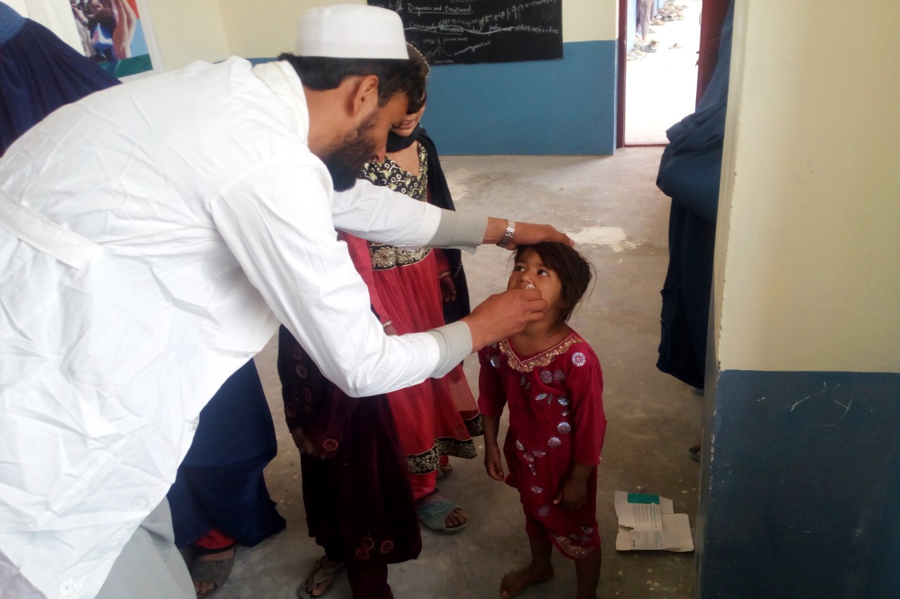 An Afghan Red Crescent volunteer administers an oral polio vaccine to a young child as part of its immunization campaign.