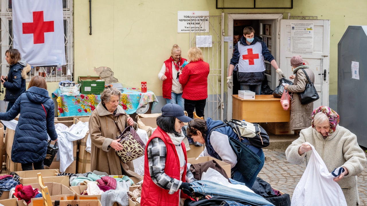 Voluntarios y voluntarias de la Cruz Roja Ucraniana reparten suministros de primera necesidad a los desplazados en Úzhhorod en mayo de 2022