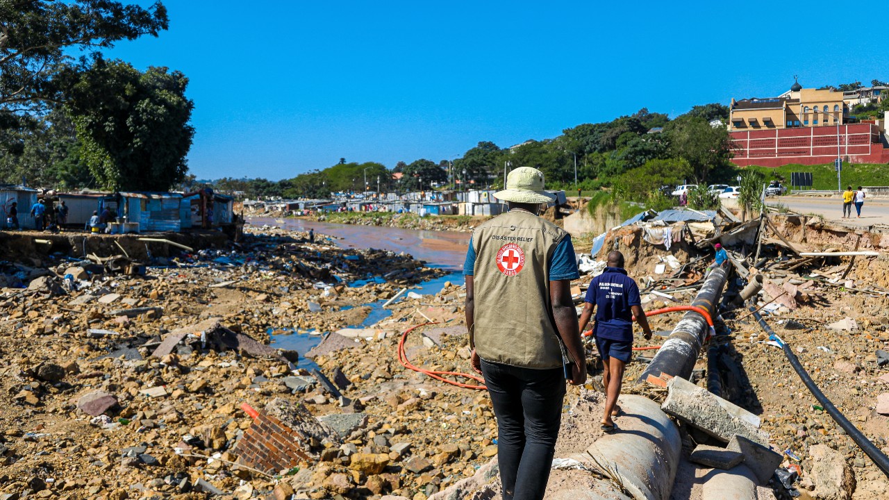 Voluntarios de la Cruz Roja Sudafricana caminan por lo que queda de Quarry Road, en la provincia de Kwazulu-Natal, destruida por las inundaciones generalizadas y devastadoras de la región en abril de 2022.