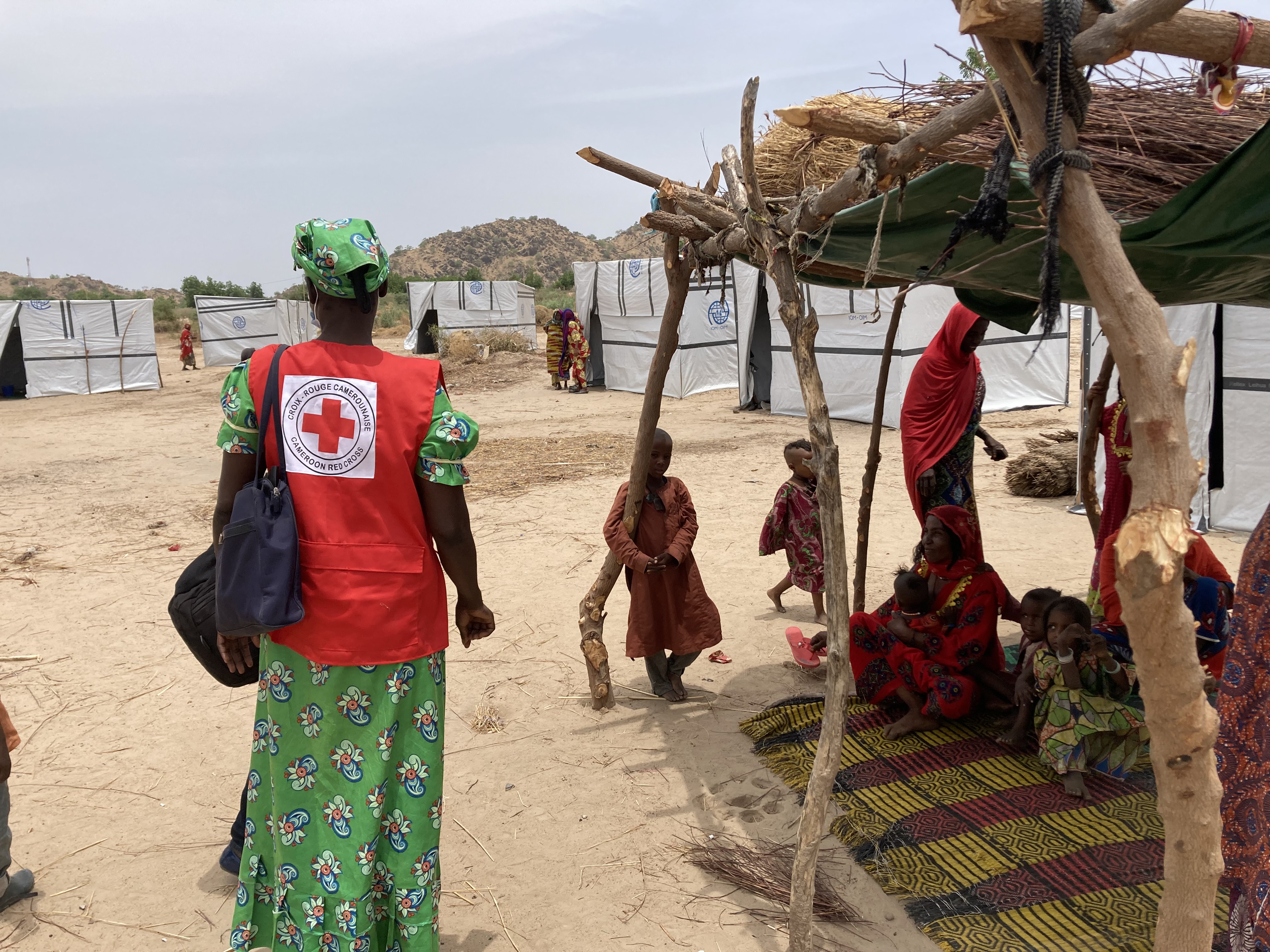A Cameroon Red Cross volunteer stands in front of internally displaced people (IDPs) from the inter-community crisis that hit several communities in the Far North region in November 2021. She has just conducted a focus group session to collect feedback from people following the distribution of non-food items.