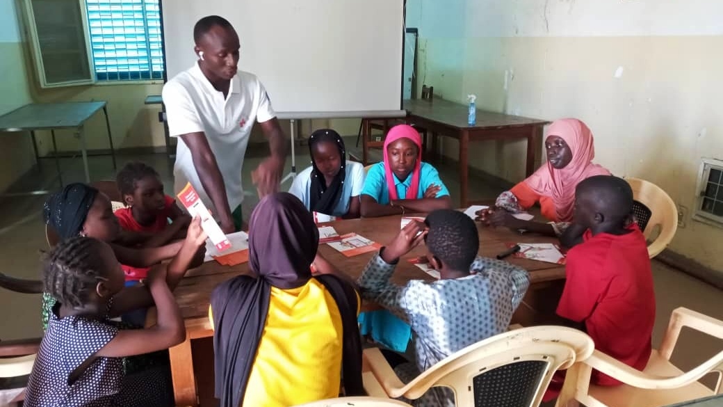 A psychosocial support worker with the Senegalese Red Cross speaks to a group of children at the Humanitarian Service Point in Kolda, Senegal