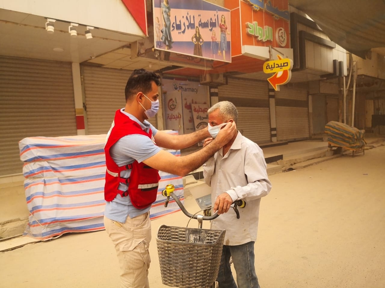 Un voluntario de la Media Luna Roja iraquí ayuda a un hombre a ponerse una mascarilla protectora durante una fuerte tormenta de arena en el país en 2022.
