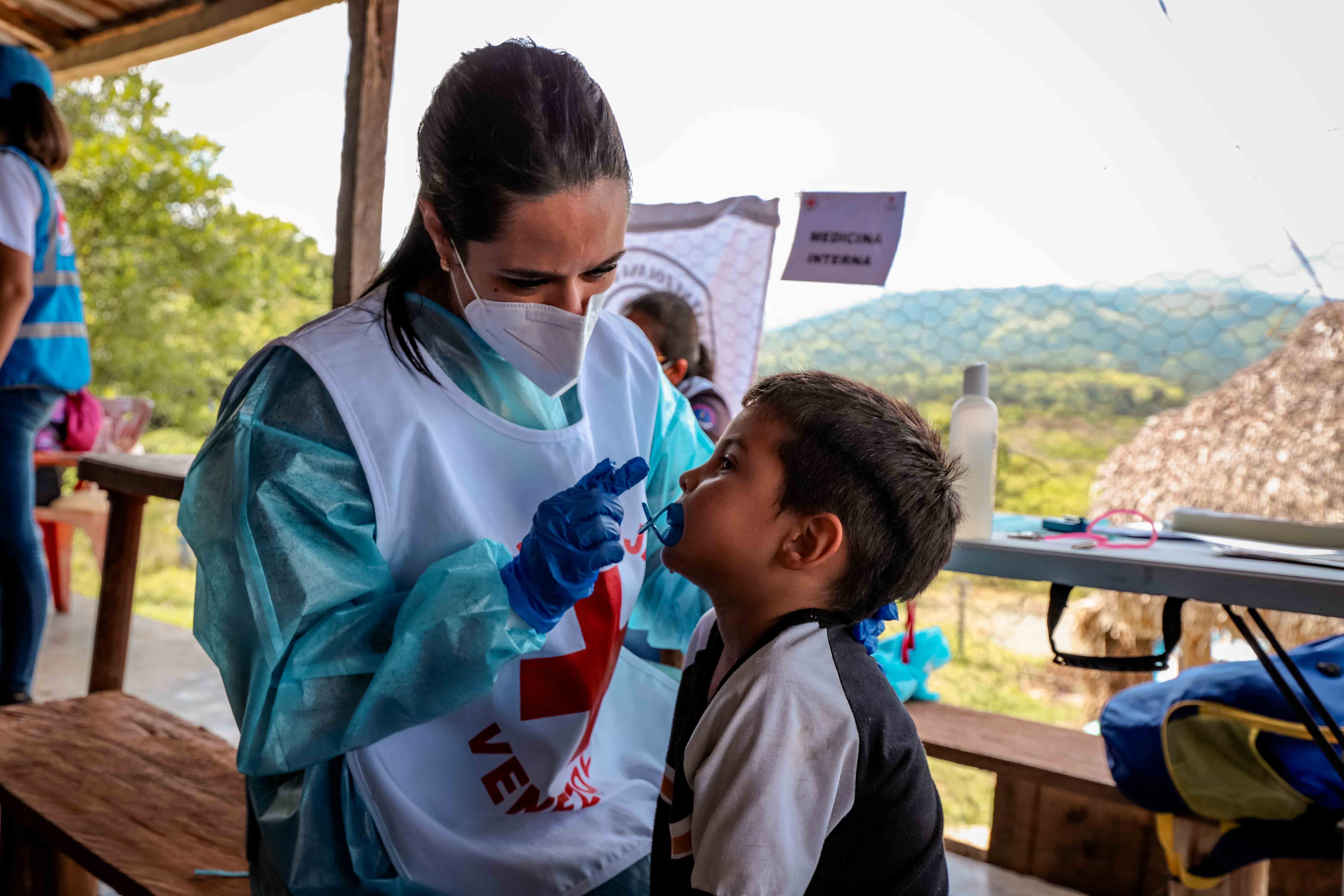 Una trabajadora sanitaria de la Cruz Roja Venezolana realiza un chequeo médico a un niño en una aldea rural del estado de Portuguesa.