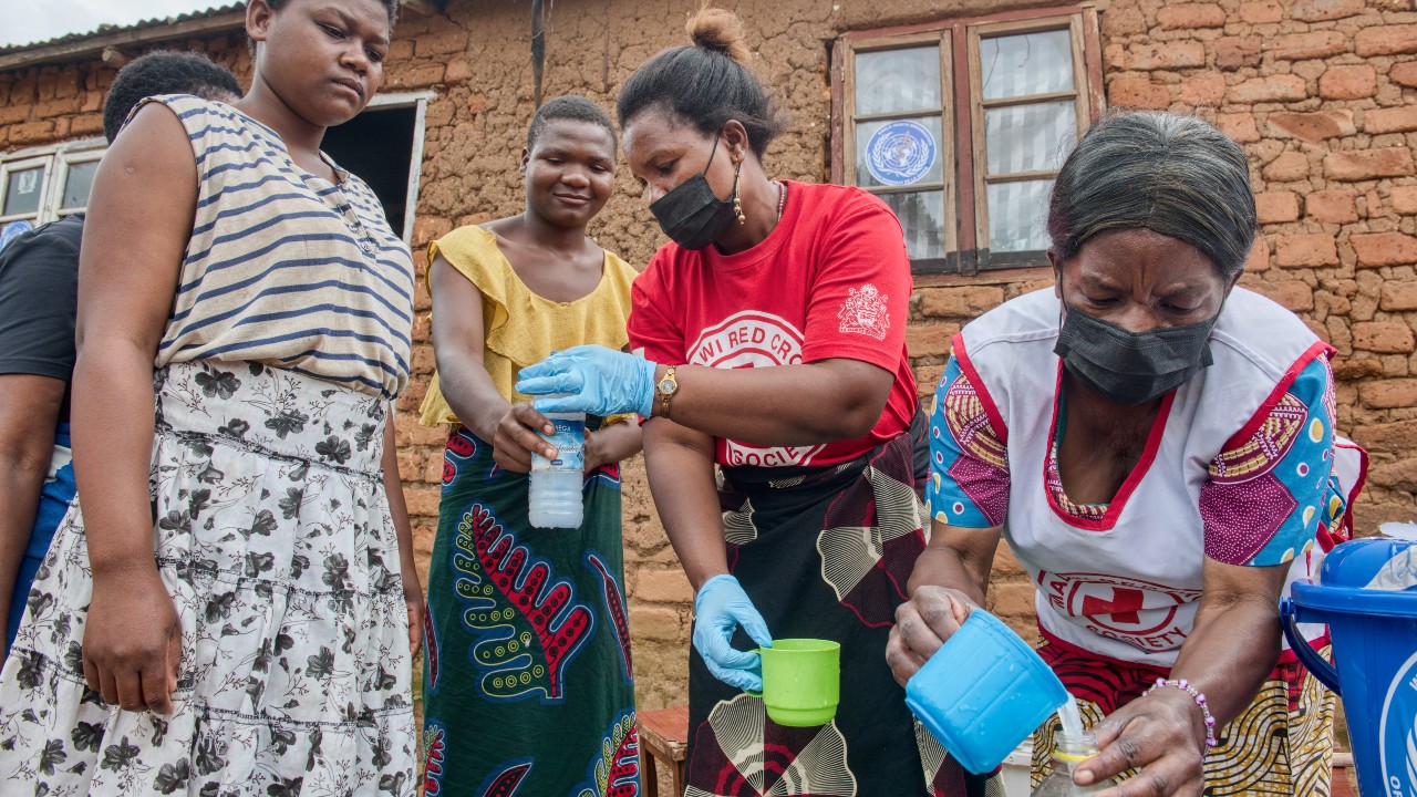 Voluntarias de la Cruz Roja de Malaui distribuyen agua clorada a los miembros de una comunidad de Blantyre en febrero de 2023.