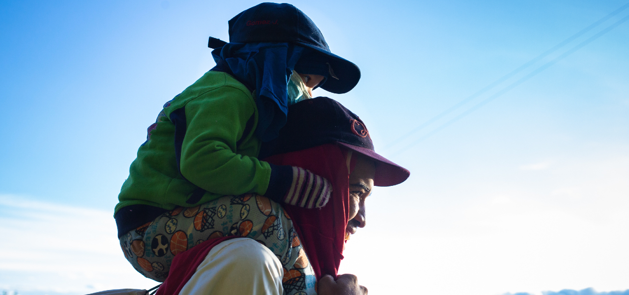 Juan from Venezuela carries his young son, Santiago, on his shoulders as they make their way on foot to Bogota, Colombia in 2018 in search of a better life.