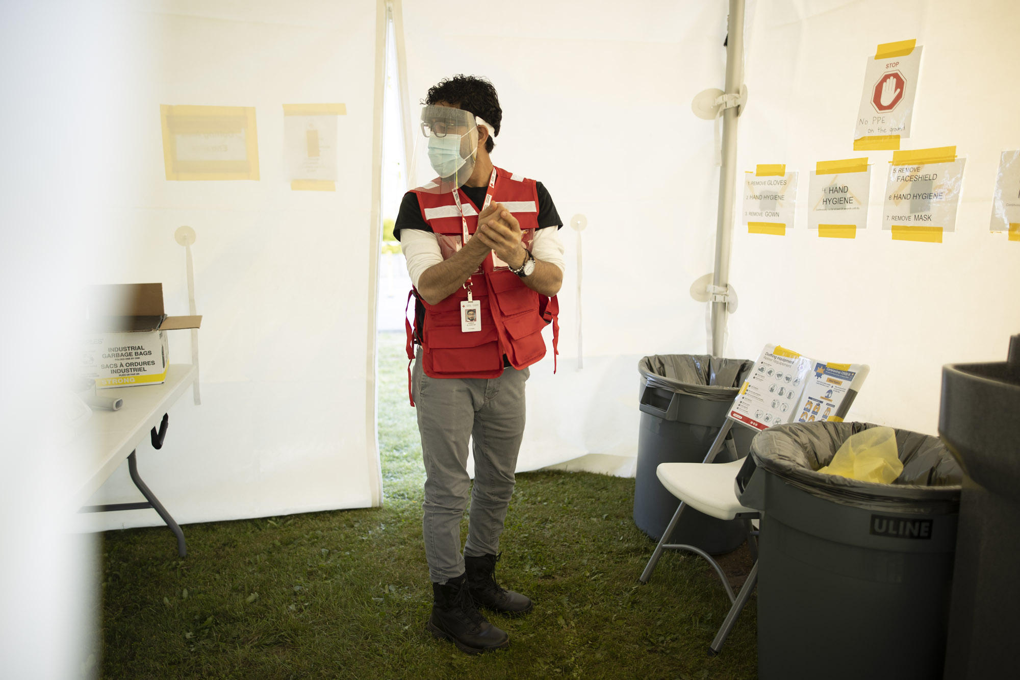 Hassan wears his Canadian Red Cross vest and sanitises his hands during his work at a COVID-19 vaccination and testing site