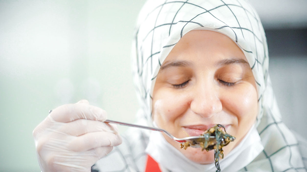 Houda, a refugee from Syria, smells food she is preparing at a Turkish Red Crescent community centre where she's taking part in a cooking course to create a new life for herself and her family in Türkiye.