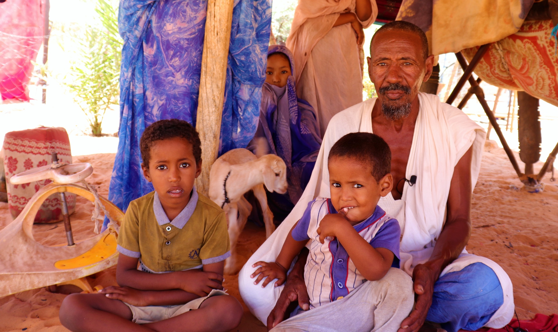 Mohamed, padre de siete, sentado con dos de sus hijos y una hija en Moudjeria (Mauritania), donde muchas personas luchan por alimentar a sus familias debido a las inundaciones de 2022 que arrasaron las cosechas.
