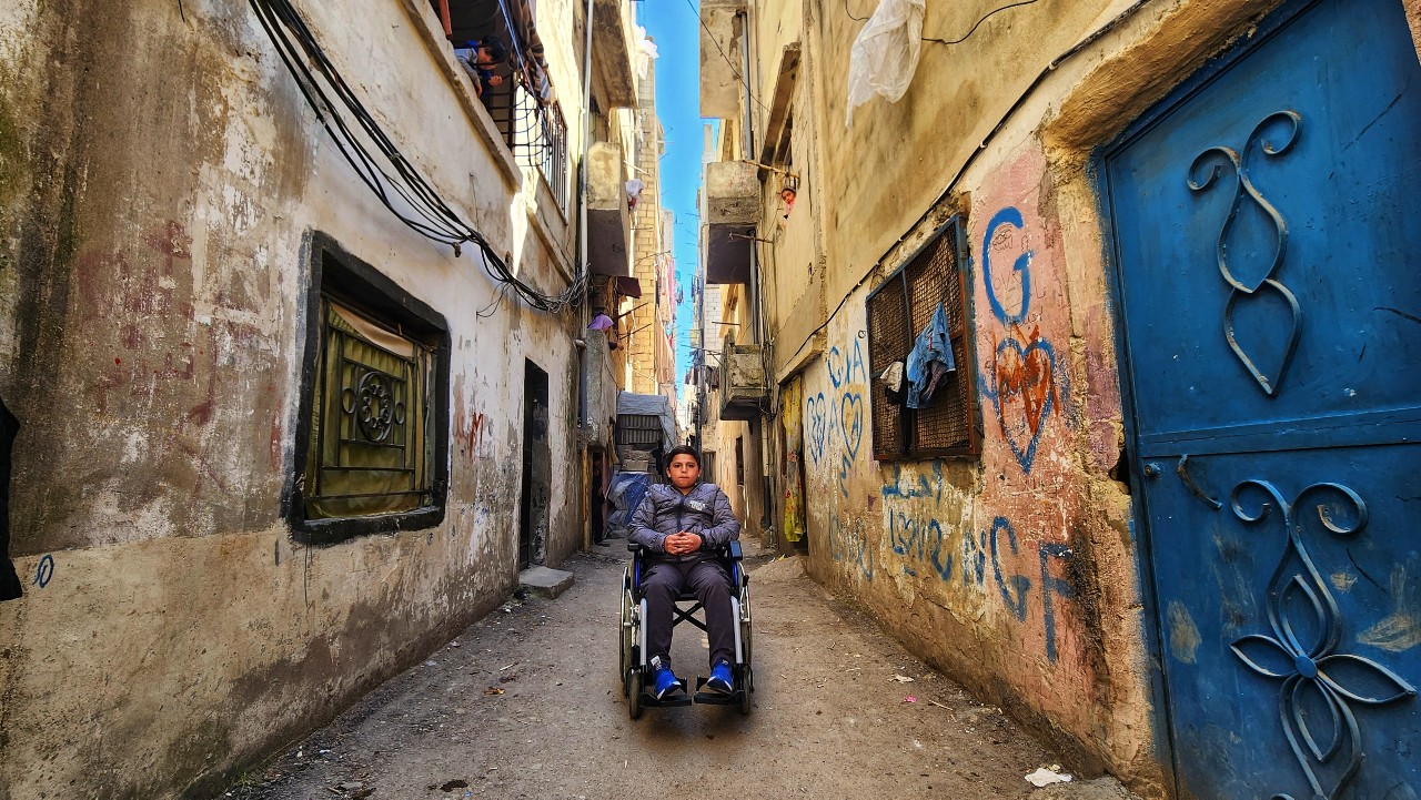 A boy in a wheelchair who was displaced by the February 2023 earthquake sits in the middle of a street in Lattakia, Syria.