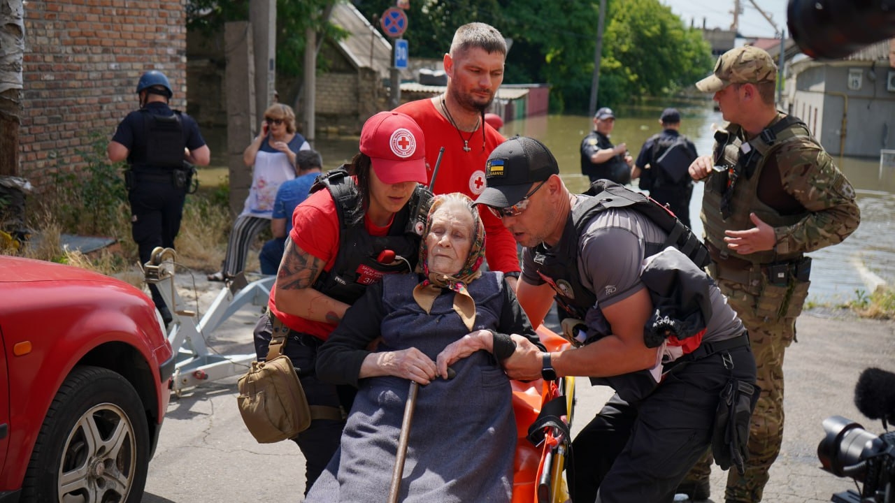 Personas voluntarias de la Cruz Roja Ucraniana ayudan a evacuar a una mujer en silla de ruedas de una zona inundada tras el derrumbe de la presa de Nova Kakhovka, el martes 6 de junio.
