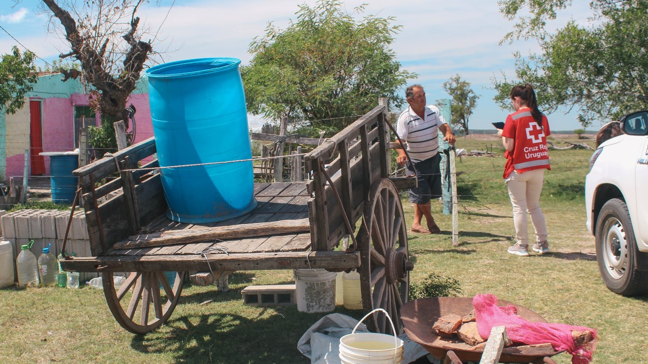 متطوع في الصليب الأحمر الأوروغوايي يتحدث إلى مزارع تأثر بالحرّ الشديد والجفاف في منطقة ريفية، وذلك لفهم المساعدات التي يحتاجها. 