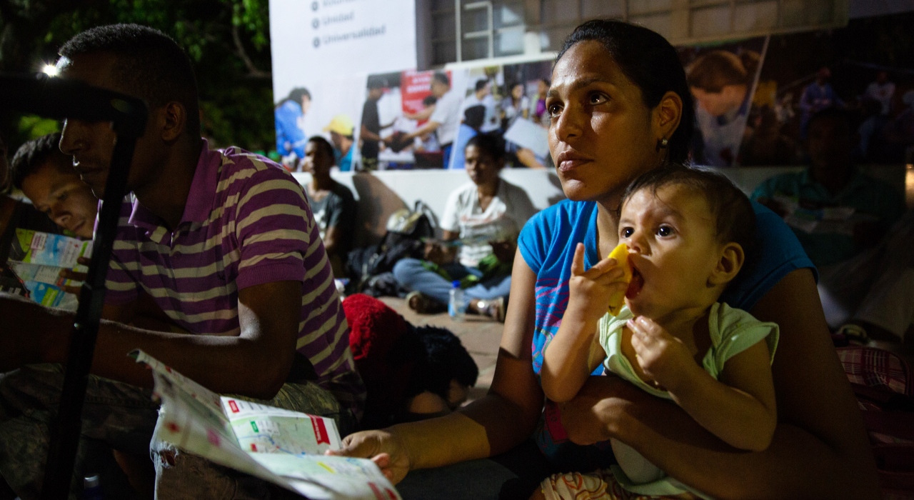 A woman from Venezuela and her child listen attentively to a Red Cross volunteer who explains the difficult journey from Cúcuta to Bucaramanga to a group of Venezuela migrants at an assistance point on the outskirts of Cúcuta in 2018.