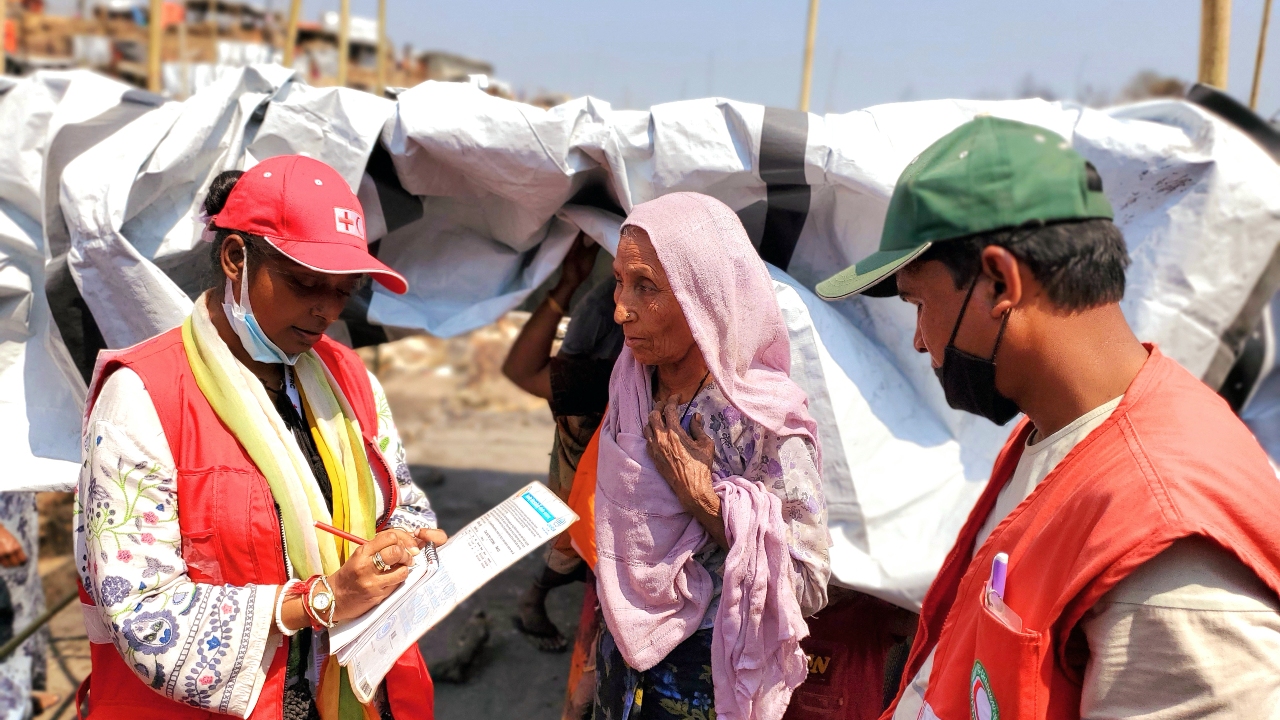 Bangladesh Red Crescent Society volunteers speak to a woman in Cox's Bazar affected by a large fire that broke out in the camp as part of a DREF operation to provide urgent relief.